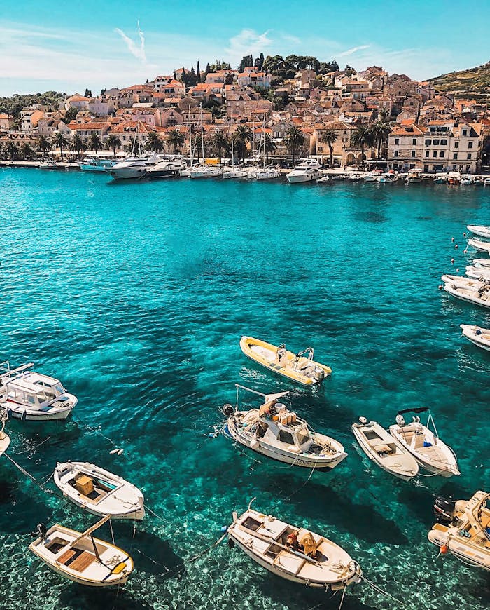 home-hero Boats in the vibrant blue waters of Hvar, Croatia, showcasing a charming coastal town under sunny skies.